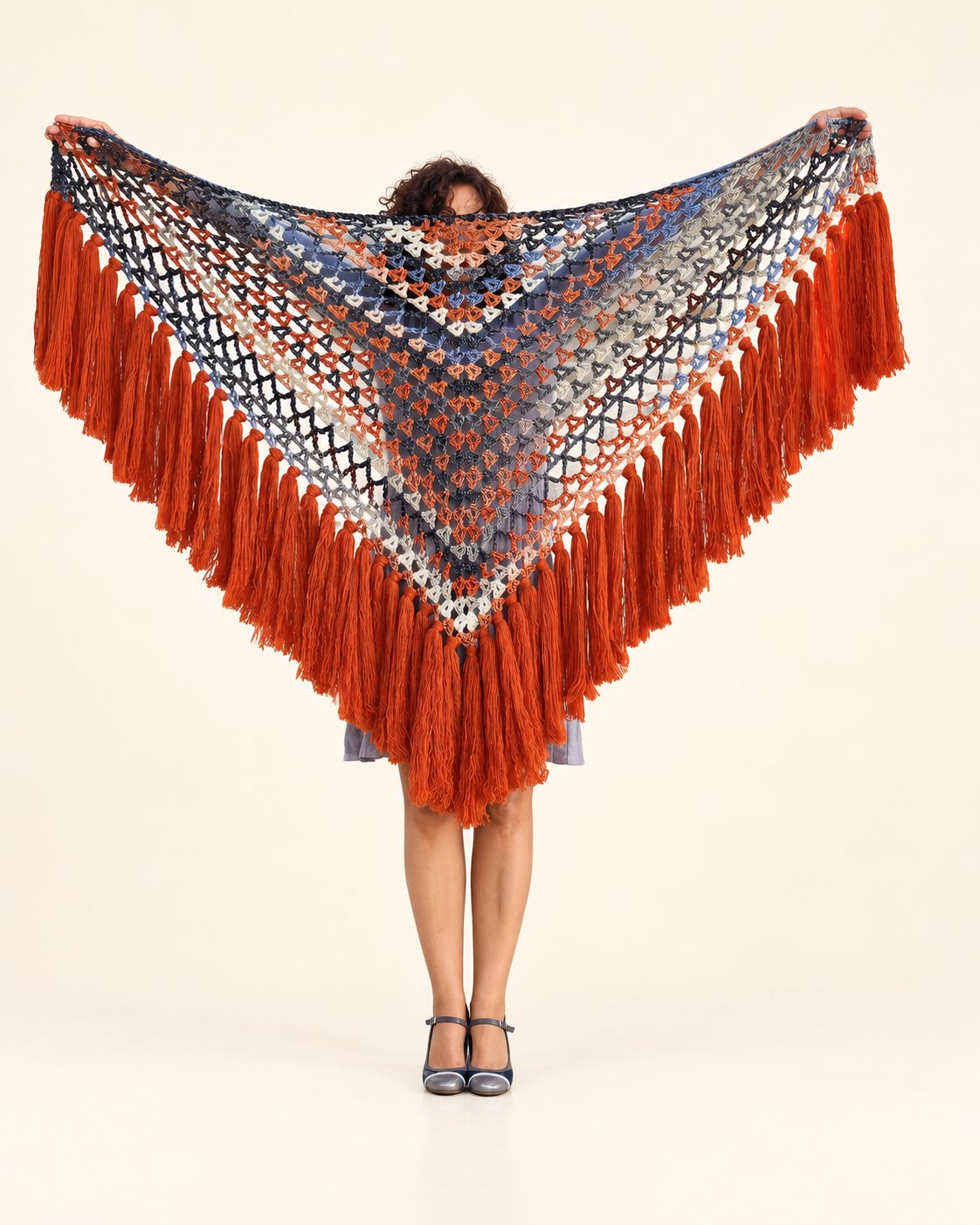 Chal Conchi de lana multicolor con flecos naranja caldera, extendido de frente sobre fondo crema