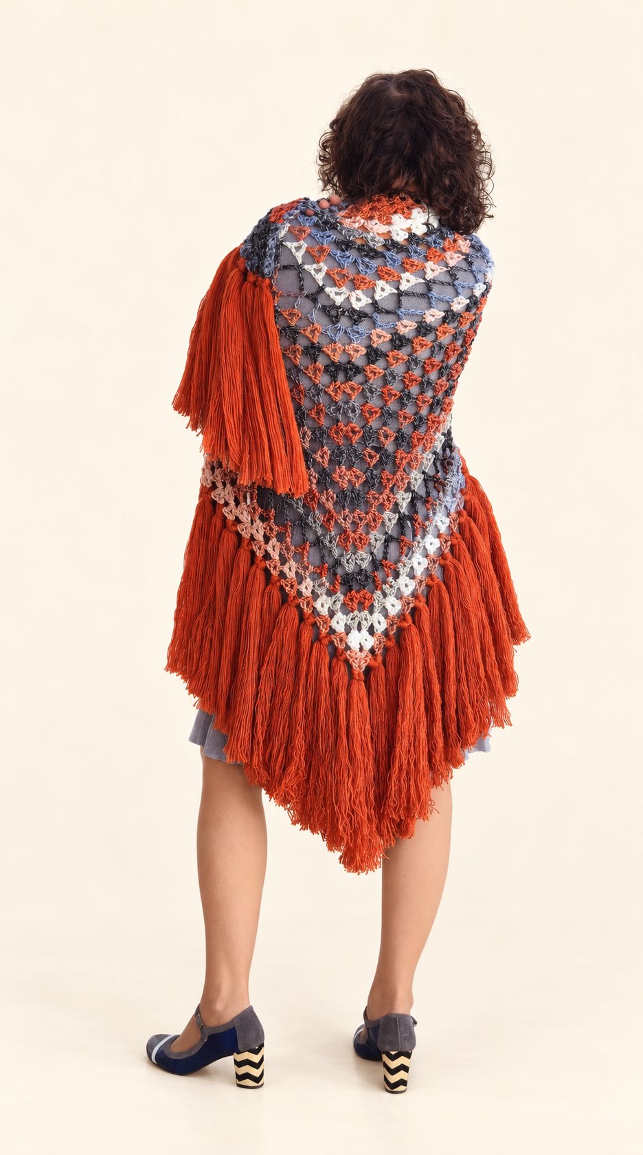 Chal Conchi de lana multicolor con flecos naranja caldera, vista de espalda sobre fondo crema