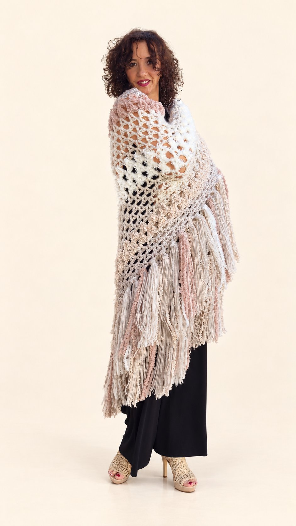 Chal Estefanía beige y rosa palo con diferentes texturas y flecos, envuelto sobre los hombros, fondo crema